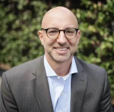 man smiling for a photo wearing glasses